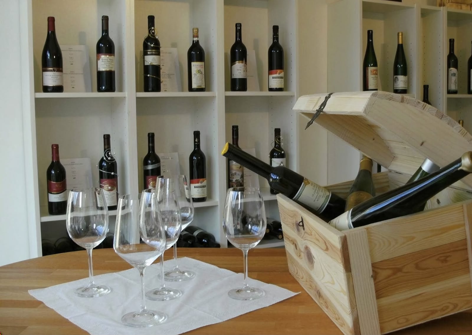 Weingläser und Flaschen vor dem Regal bei Mosel Wein